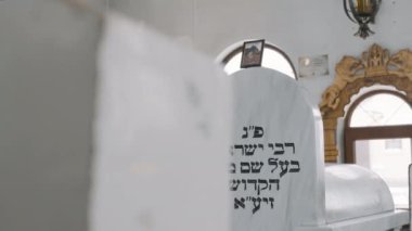 Medzhybizh 'deki eski Yahudi Mezarlığı. Kamera sağa doğru hareket ediyor. Binanın duvarındaki yazı, Baal Şem Tov 'un gömüldüğü yer.