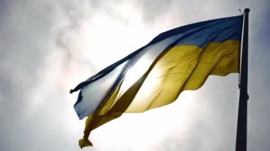 Arka planda Ukrayna bayrağı. Rüzgar mavi ve sarı bayrağı dalgalandırıyor güzel kabarık bulutların arka planında.