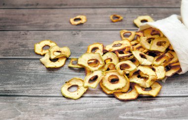 Kurutulmuş elmalar ahşap bir masada poşetten halkalara dökülür.