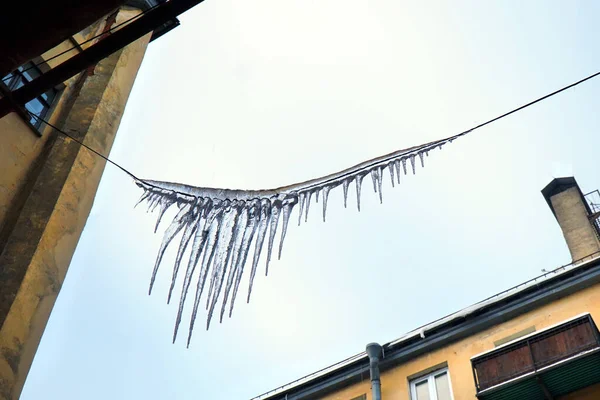 Mavi gökyüzüne karşı kabloda buz sarkıtları.