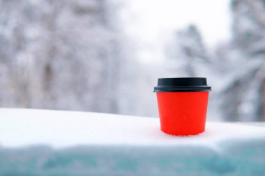 Kahve için kırmızı bardak ya da kışın karda çay orman ve doğanın arka planına karşı. Boşluğu kopyala