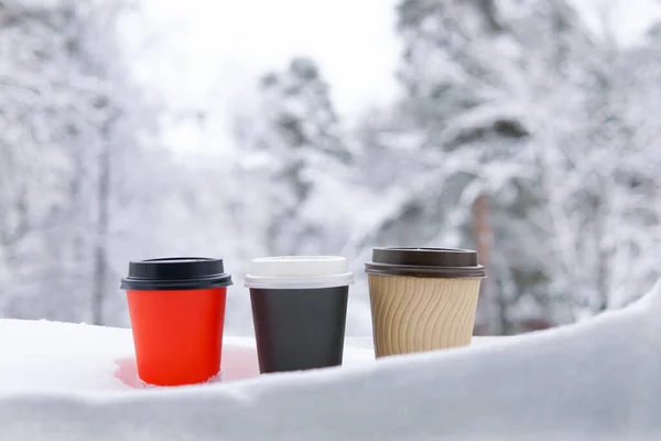 Kış ormanının arka planında karlı üç bardak kahve..