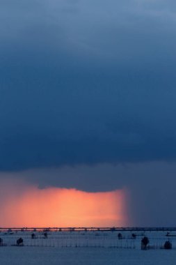 Şiddetli yağmur bulutları karanlık ama güneşin ışığı da parlıyor.