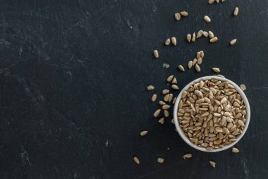 Saf ayçiçeği çekirdekleri ve çekirdekleri olan kase fotokopi alanı olan bir levha üzerine yayılmış.