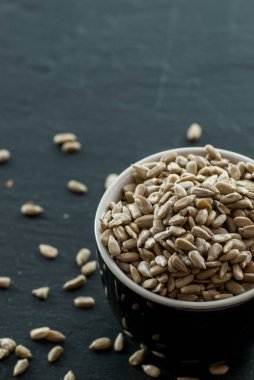 Saf ayçiçeği çekirdekleri ve çekirdekleri olan kase fotokopi alanı olan bir levha üzerine yayılmış.