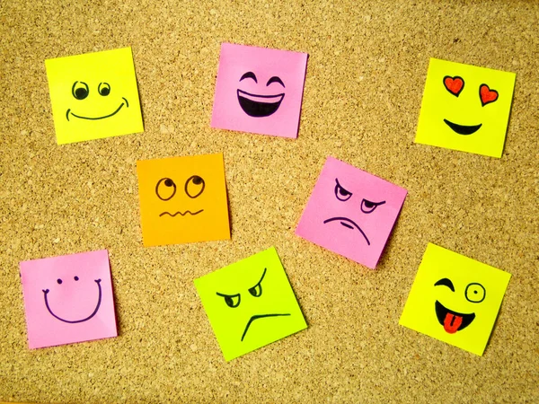 Kendine yapıştırıcı ofis notları ve mantar panoda farklı yüz ifadeleri soyut konsept fotoğraf olarak