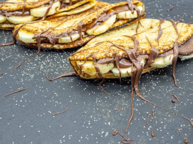 Muz dilimleri ve çikolata ile servis edilen krepler.