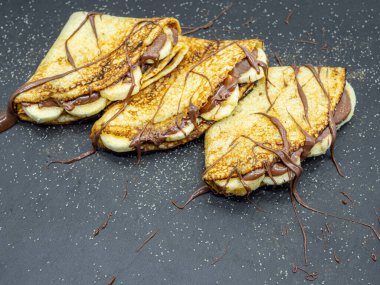 Muz dilimleri ve çikolata ile servis edilen krepler.