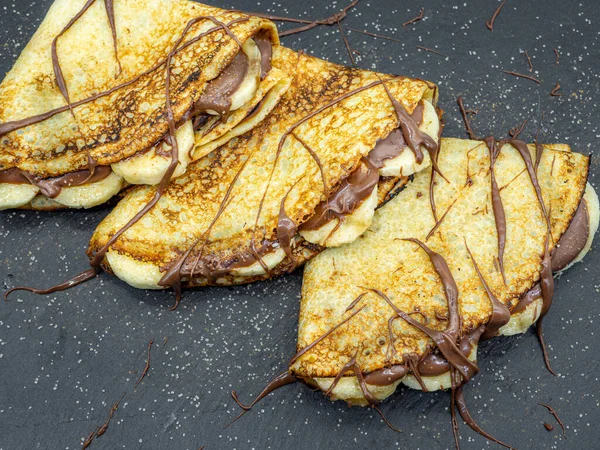 Muz dilimleri ve çikolata ile servis edilen krepler.