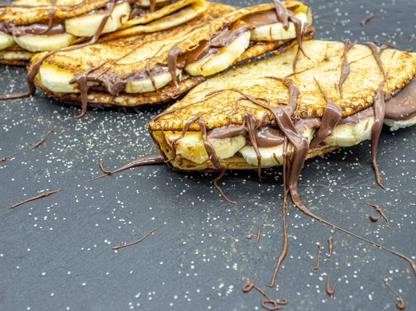 Muz dilimleri ve çikolata ile servis edilen krepler.