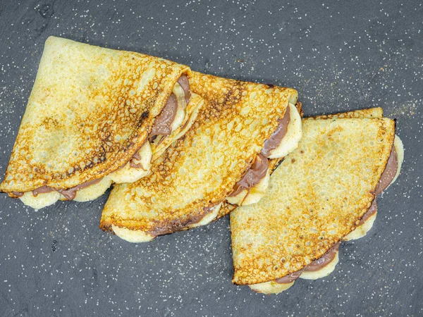 Muz dilimleri ve çikolata ile servis edilen krepler.