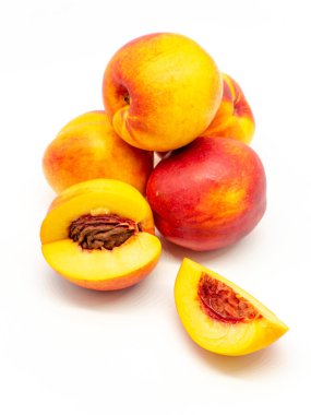 Dilimlenmiş ve tüm nektarinler beyaz arkaplanda yığılmış.