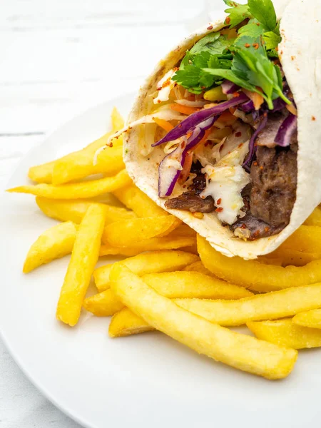 Patates kızartması ve beyaz tabakta servis edilen bir shawarma.