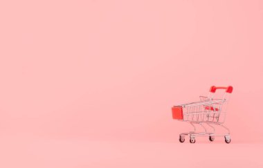 Alışveriş konsepti: pembe arka planda boş kırmızı alışveriş arabası. Çevrimiçi alışveriş tüketicileri evden ve teslimat servisinden alışveriş yapabilirler. kopyalama alanı ile