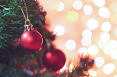 Noel süsü. Çam dallarında asılı kırmızı toplar Noel ağacı çelengi ve soyut bokeh arka planında fotokopi ile süslenmiş süsler.