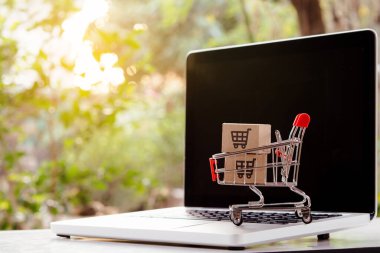 İnternetten alışveriş. Laptop klavyesinde bir tramvayda alışveriş arabasının logosu olan karton kutu. İnternet 'te alışveriş servisi. Eve teslim etmeyi teklif ediyor