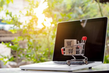 İnternetten alışveriş. Laptop klavyesinde bir tramvayda alışveriş arabasının logosu olan karton kutu. İnternet 'te alışveriş servisi. Eve teslim etmeyi teklif ediyor