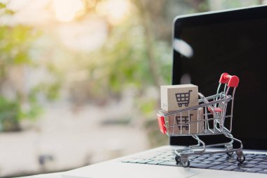 İnternetten alışveriş. Laptop klavyesinde bir tramvayda alışveriş arabasının logosu olan karton kutu. İnternet 'te alışveriş servisi. Eve teslim etmeyi teklif ediyor