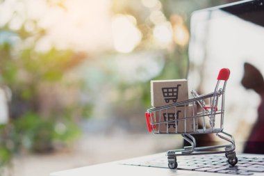 İnternetten alışveriş. Laptop klavyesinde bir tramvayda alışveriş arabasının logosu olan karton kutu. İnternet 'te alışveriş servisi. Eve teslim etmeyi teklif ediyor