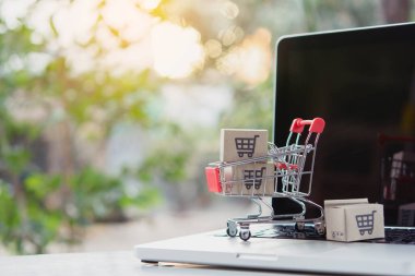 İnternetten alışveriş. Laptop klavyesinde bir tramvayda alışveriş arabasının logosu olan karton kutu. İnternet 'te alışveriş servisi. Eve teslim etmeyi teklif ediyor
