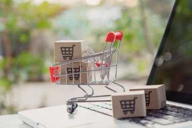 İnternetten alışveriş. Laptop klavyesinde bir tramvayda alışveriş arabasının logosu olan karton kutu. İnternet 'te alışveriş servisi. Eve teslim etmeyi teklif ediyor