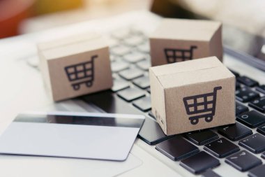 İnternetten alışveriş. Kredi kartı ve klavyede alışveriş arabasının logosu olan karton kutu. İnternet 'te alışveriş servisi. Eve teslimat teklif ediyor