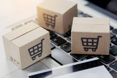 İnternetten alışveriş. Kredi kartı ve klavyede alışveriş arabasının logosu olan karton kutu. İnternet 'te alışveriş servisi. Eve teslimat teklif ediyor