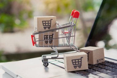 İnternetten alışveriş. Laptop klavyesinde bir tramvayda alışveriş arabasının logosu olan karton kutu. İnternet 'te alışveriş servisi. Eve teslim etmeyi teklif ediyor