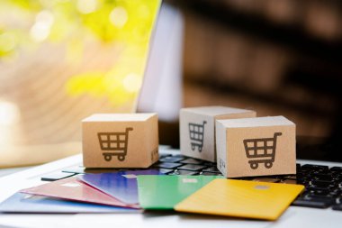 İnternetten alışveriş. Kredi kartı ve klavyede alışveriş arabasının logosu olan karton kutu. İnternet 'te alışveriş servisi. Eve teslimat teklif ediyor