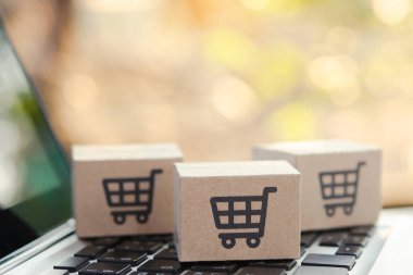 İnternetten alışveriş. Laptop klavyesinde alışveriş arabasının logosu olan karton kutu. İnternet 'te alışveriş servisi. Eve teslimat teklif ediyor