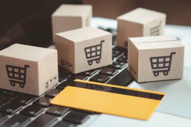 İnternetten alışveriş. Kredi kartı ve klavyede alışveriş arabasının logosu olan karton kutu. İnternet 'te alışveriş servisi. Eve teslimat teklif ediyor