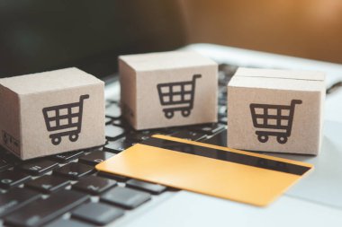 İnternetten alışveriş. Kredi kartı ve klavyede alışveriş arabasının logosu olan karton kutu. İnternet 'te alışveriş servisi. Eve teslimat teklif ediyor