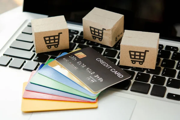 Shopping online. Credit card and cardboard box with a shopping cart logo on laptop keyboard. Shopping service on The online web. offers home delivery