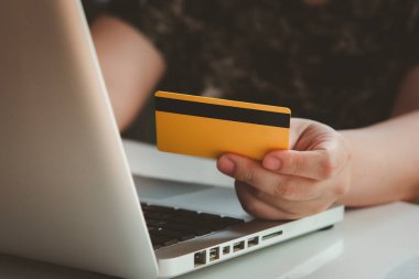 Kredi kartı ödemesi. Kadın elleri kredi kartı tutuyor ve dizüstü bilgisayar kullanıyor. İnternetten alışveriş