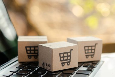 İnternetten alışveriş. Laptop klavyesinde alışveriş arabasının logosu olan karton kutu. İnternet 'te alışveriş servisi. Eve teslimat teklif ediyor