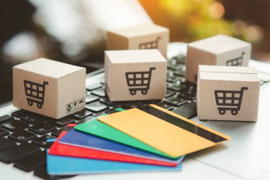 İnternetten alışveriş. Kredi kartı ve klavyede alışveriş arabasının logosu olan karton kutu. İnternet 'te alışveriş servisi. Eve teslimat teklif ediyor