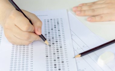 Öğrenciler, cevap kağıtları ve matematik soru kağıtları üzerinde seçilmiş kalemle yazı yazma seçeneğini el ele tutuyorlar. Sınav yapan öğrenciler. okul sınavı