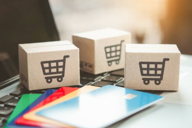 İnternetten alışveriş. Kredi kartı ve klavyede alışveriş arabasının logosu olan karton kutu. İnternet 'te alışveriş servisi. Eve teslimat teklif ediyor