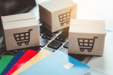 İnternetten alışveriş. Kredi kartı ve klavyede alışveriş arabasının logosu olan karton kutu. İnternet 'te alışveriş servisi. Eve teslimat teklif ediyor