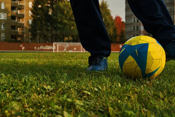 Játékos rugdossa a labdát, miközben focizik a zöld füves pályán. — Stock Fotó