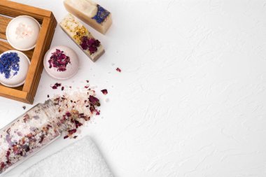 Güzel el yapımı sabun, tuz ve bomba külçeleri beyaz ahşap bir arka planda.