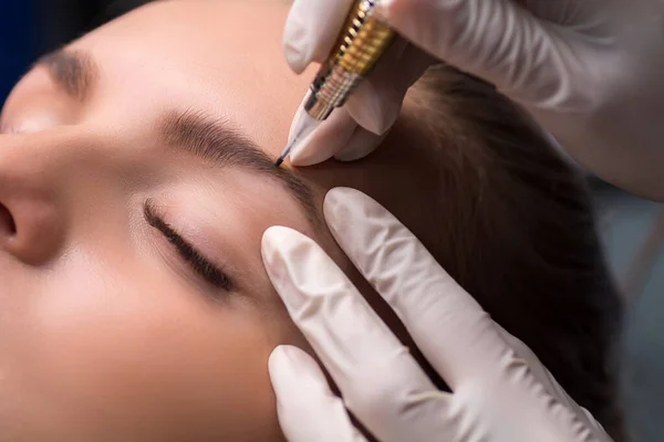 Permanent eyebrow makeup. Cosmetologist applying tattooing of eyebrows.