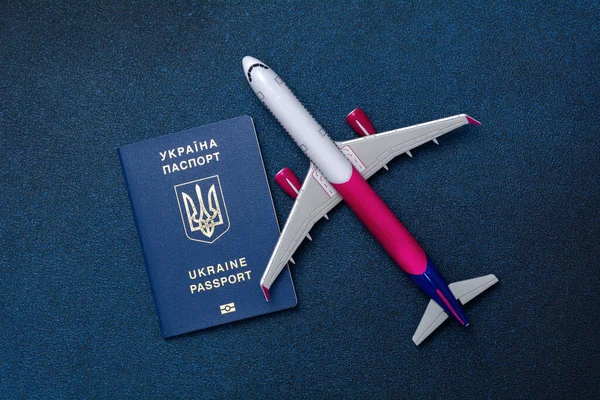 Passport of Ukraine and a small model aircraft. The concept of going abroad, refugees, people are fleeing the country, war in Ukraine. Russia attacked Ukraine.