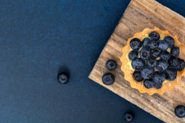 Blueberry pie on a wooden board. Blueberry tart. Focus on the berry dessert. Flat lay top view.