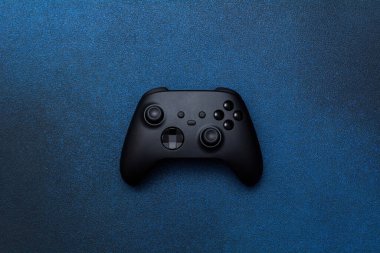 Game controller on a blue background. Black joystick for computer games top view.