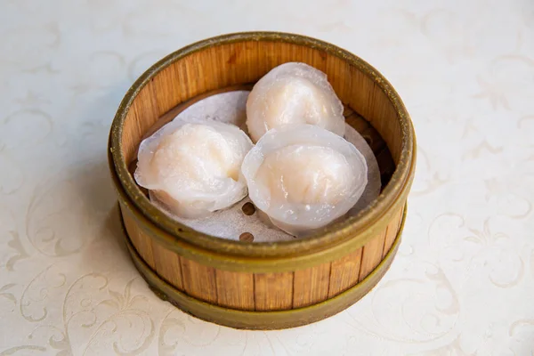 Crystal pyramid dumplings dim sum of traditional Cantonese yum-cha dim sum Asian gourmet cuisine meal food dish in the steam basket container and white table