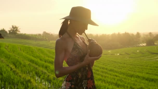 Mujer joven con coco en vestido negro caminando en campos de arroz Bali — Vídeos de Stock