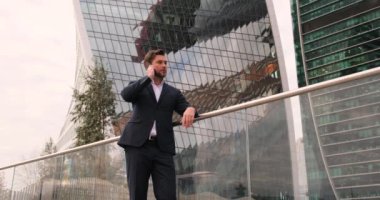 Yakışıklı İşadamı modern ofis binasının yanındaki akıllı telefonuna bakıyor.