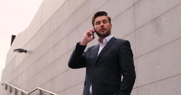 Mosolygó üzletember beszél a mobilján. a főnök egy üzleti öltönyben — Stock videók