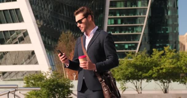L'homme tenant la tasse de café marchant en plein air au bureau avec le sourire sac visage — Video